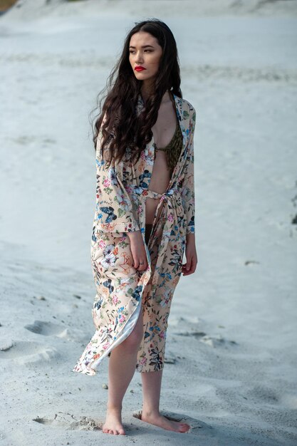 Una mujer con un vestido floral se encuentra en una playa.