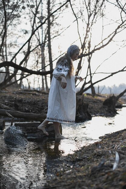 Foto mujer en vestido folclórico ucraniano caminando sobre el agua fotografía escénica