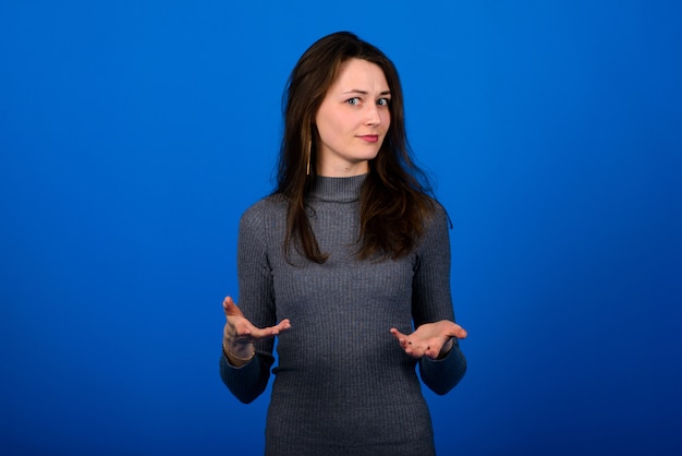 Mujer en vestido gris sobre fondo azul