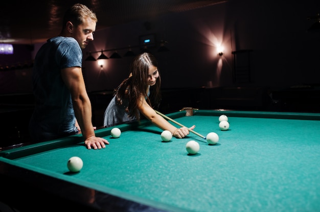 Mujer en vestido jugando al billar con un hombre en un pub.