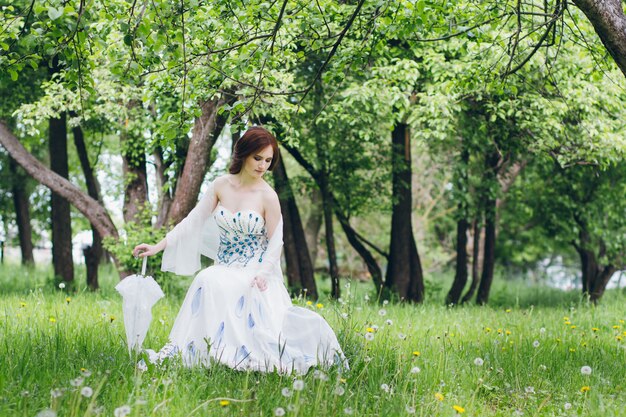 Mujer con vestido largo y blanco en el jardín de verano