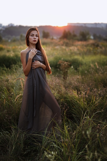 Mujer con un vestido largo gris al atardecer