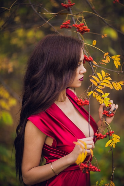 Mujer en un vestido largo rojo solo en el bosque. Fabulosa y misteriosa imagen de una niña en un bosque oscuro en el sol de la tarde. Sunset, Princess se perdió.