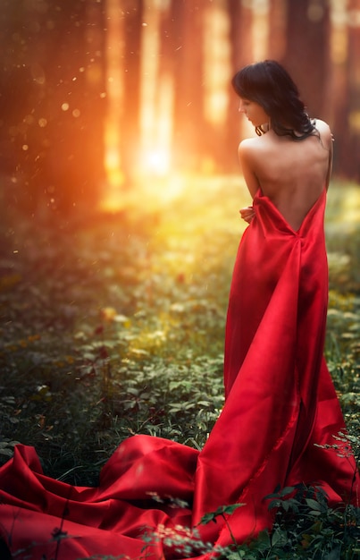 Mujer en un vestido largo rojo solo en el bosque