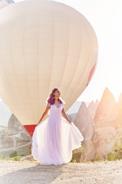 Foto mujer con un vestido largo sobre fondo de globos en capadocia