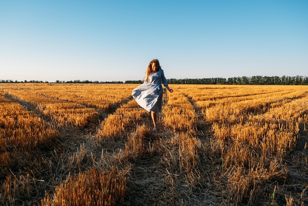 Mujer en vestido de lino azul disfrutando de la naturaleza en el estrés del campo al atardecer y el gasto de resiliencia psicológica