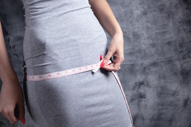 Mujer en vestido mide su cintura