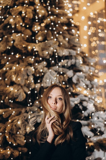 mujer, en, vestido negro, cerca, árbol de navidad