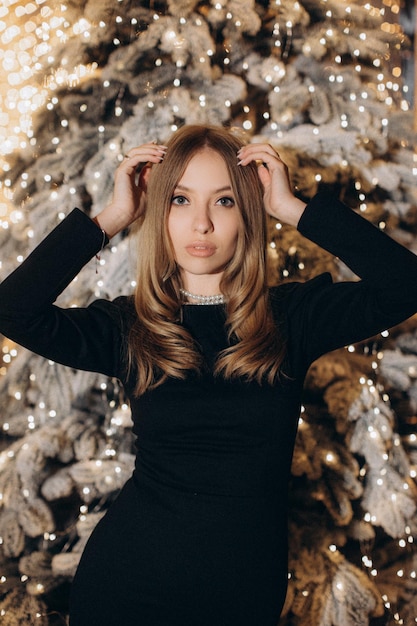 mujer, en, vestido negro, cerca, árbol de navidad