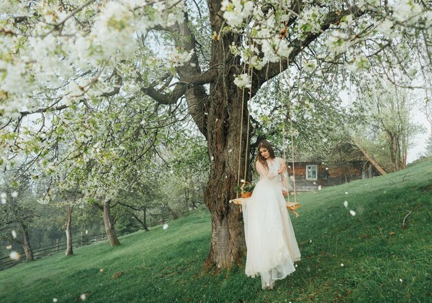 Mujer con vestido de novia blanco sobre fondo de árbol floreciente. novia en boda al aire libre en primavera. retrato de mujer