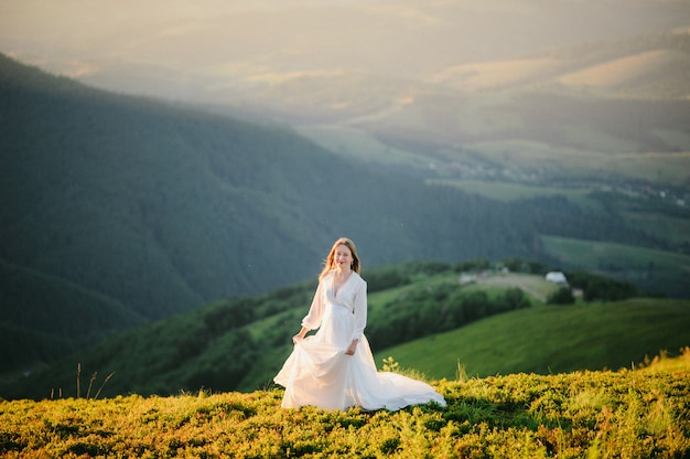 Mujer en un vestido de novia corre por el campo hacia las montañas