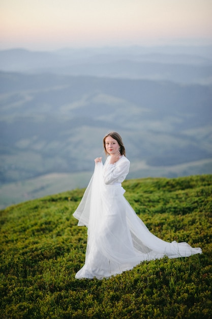 Mujer en un vestido de novia corre por el campo hacia las montañas