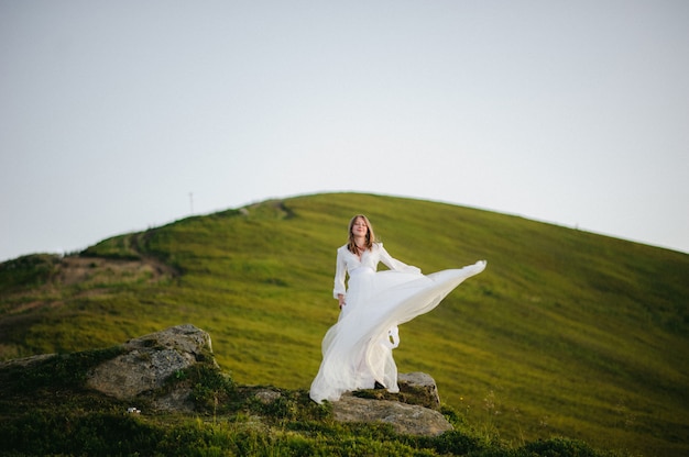 Mujer en un vestido de novia corre por el campo hacia las montañas