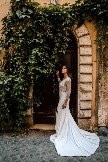 Una mujer en un vestido de novia debajo de un arco de hiedra