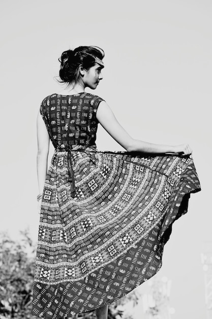 Mujer con vestido de pie contra el cielo