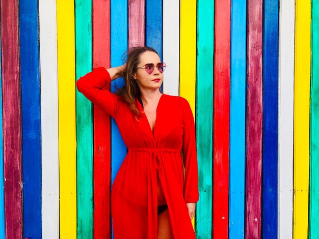 Foto mujer en vestido de pie contra la pared de varios colores