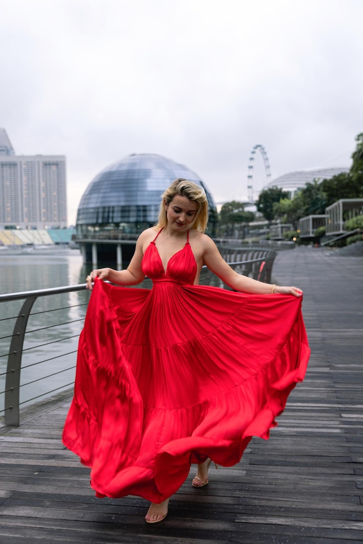 Foto una mujer con un vestido rojo baila frente a una rueda de la fortuna.