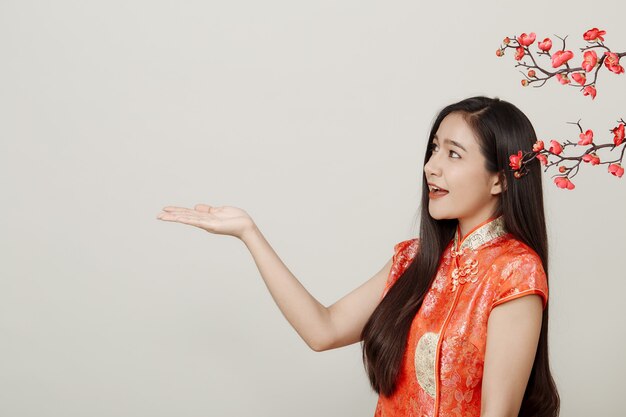 Mujer en vestido rojo chino tradicional con flores de ciruela