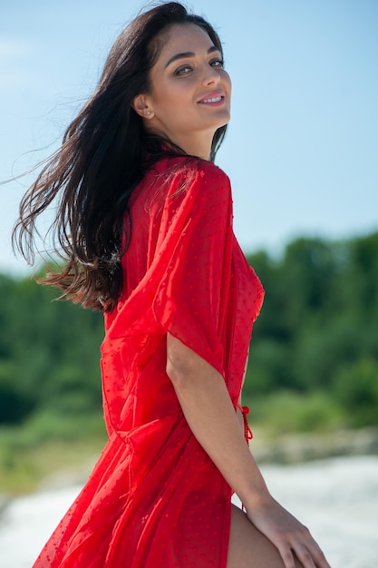 Una mujer con un vestido rojo se encuentra en una playa.