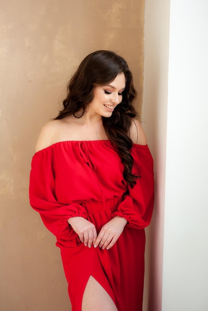 Una mujer con un vestido rojo se para frente a una pared.