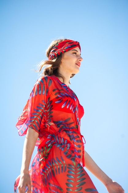 Una mujer con un vestido rojo con un pañuelo y una hoja de palma en la cabeza.