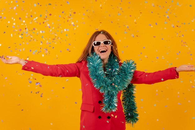 Mujer en vestido rojo sobre un fondo amarillo lanzando con concepto de fiesta de confeti