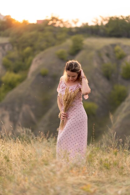 Mujer en un vestido rosa con un ramo de trigo