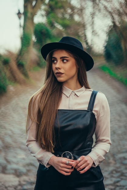 Mujer con vestido y sombrero posando afuera