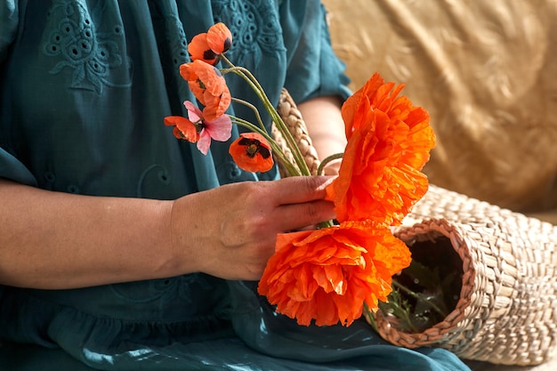 Mujer en vestido verde sosteniendo flores poppe, de cerca en sus manos. Sueños de primavera.