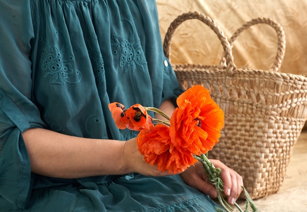 Mujer en vestido verde sosteniendo flores poppe, de cerca en sus manos. Sueños de primavera.