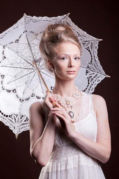 Mujer en vestido vintage sosteniendo un paraguas de encaje. Rico y añejo. Lujo y elegancia. Foto de estudio