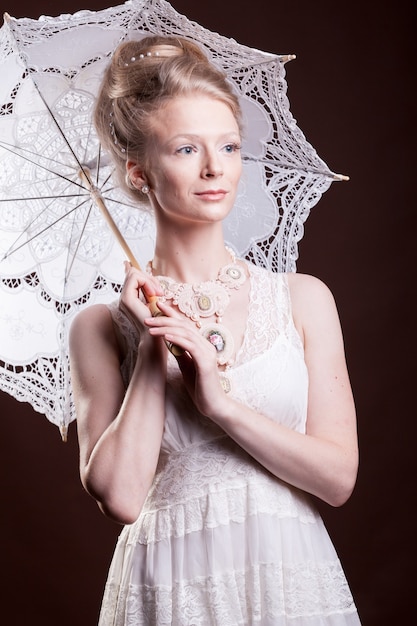Mujer en vestido vintage sosteniendo un paraguas de encaje. Rico y añejo. Lujo y elegancia. Foto de estudio