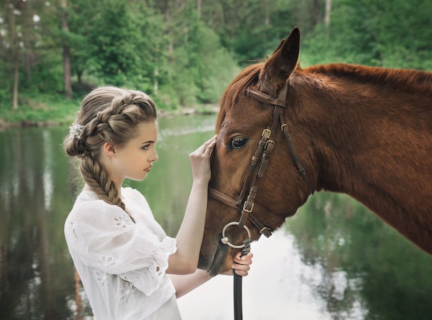 Mujer en vestido vintage tocando a cara de caballo