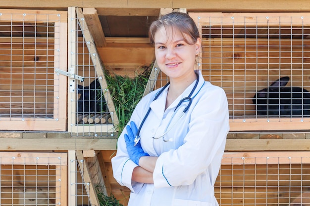 Mujer veterinaria con estetoscopio en el fondo del rancho del granero médico veterinario comprobar conejo en e ...