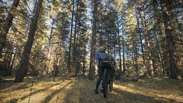 La mujer viaja en cicloturismo de terreno mixto con bicicleta bikepacking El viaje del viajero con bolsas de bicicleta Parque forestal mágico