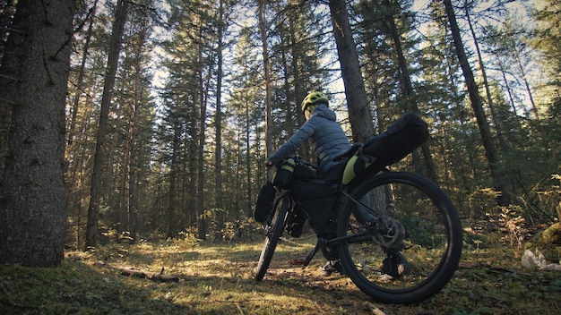 La mujer viaja en cicloturismo de terreno mixto con bicicleta bikepacking. El viajero viaja con bolsas para bicicletas. Parque forestal mágico.