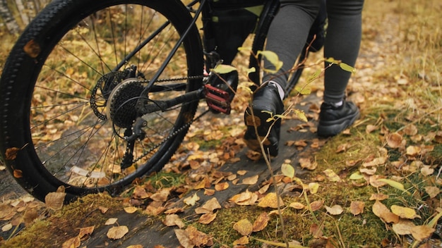 La mujer viaja en cicloturismo de terreno mixto con bikepacking El viaje del viajero con bolsas de bicicleta Ropa deportiva en colores verdes negros El viaje en el mágico bosque de otoño Río puente de madera