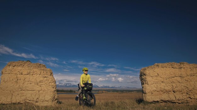 La mujer viaja en cicloturismo de terreno mixto con bikepacking El viaje del viajero con bolsas para bicicletas Sport bikepacking ropa deportiva para bicicletas en colores verdes y negros Arco de piedra cubierto de nieve de montaña