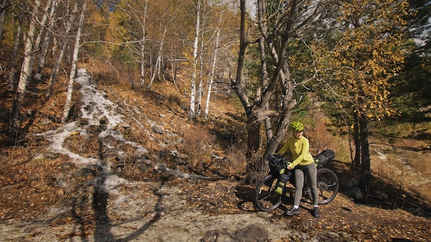 La mujer viaja en cicloturismo de terreno mixto con bikepacking. El viajero viaja con bolsas para bicicletas. Bikepacking de turismo deportivo.