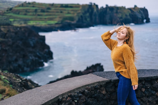 Una mujer viaja a lugares tropicales. Se para contra el fondo de un lago, el viento desarrolla su cabello.