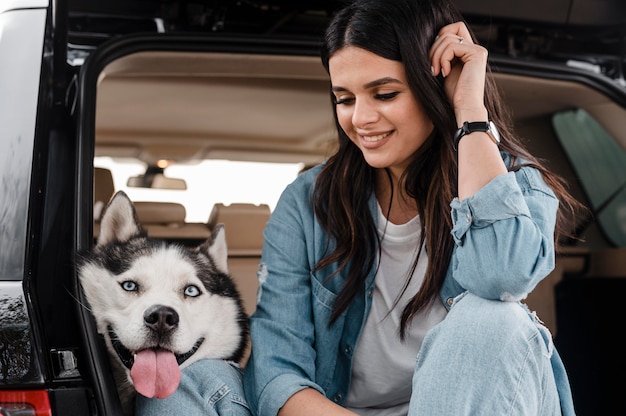 Foto mujer viajando en coche con su lindo husky