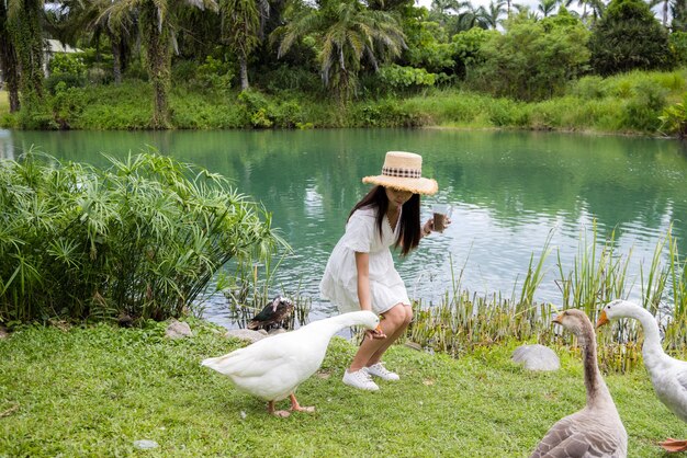 Mujer de viaje alimenta al ganso al lado del lago