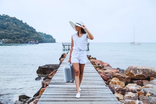 Mujer de viaje con maleta en la playa