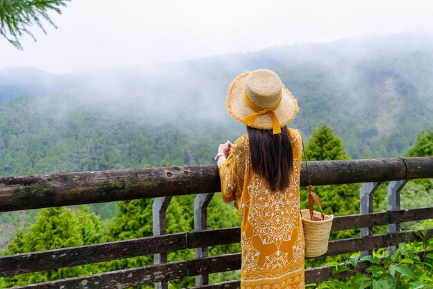 Foto mujer de viaje mira el paisaje en el bosque