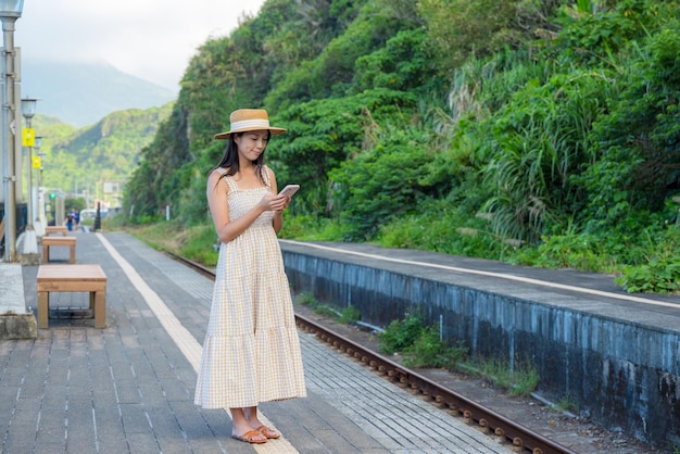 Mujer de viaje usa teléfono móvil para comprobar el horario del tren