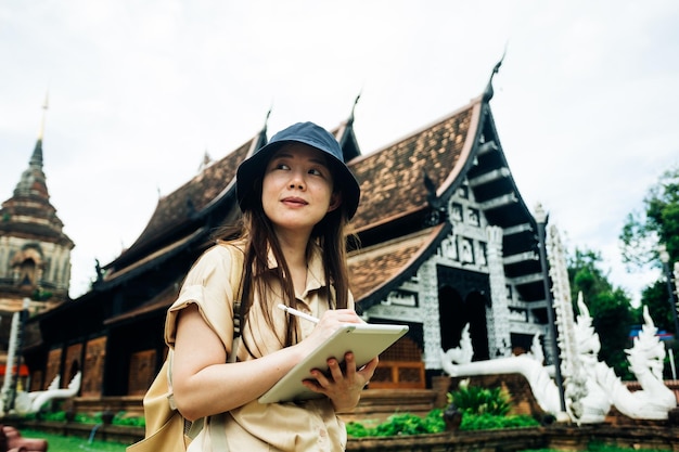 Mujer viajera asiática con una tableta en el templo ok moli en la provincia de Chiang Mai, Tailandia