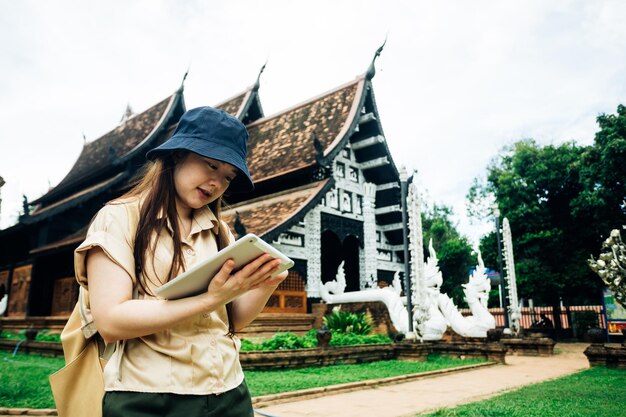 Mujer viajera asiática con una tableta en el templo ok moli en la provincia de Chiang Mai, Tailandia