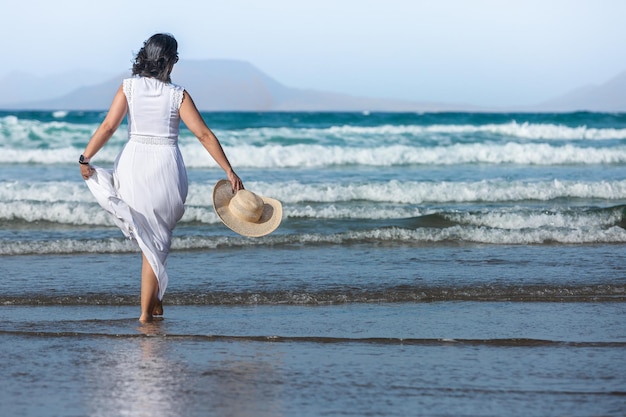 Mujer viajera caminando cerca de las olas del mar