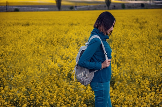 Mujer viajera en un campo de colza en flor