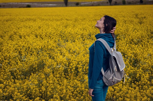 Mujer viajera en un campo de colza en flor